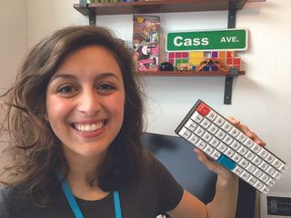 An image of Cassidy Williams smiling and holding up her Scrabble keyboard side project.