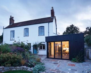 extension on a house made from black material with big windows shown from backyard