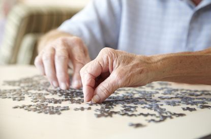 Elderly couple, aged 75-80, looking for pieces of a jigsaw puzzle in a private retirement home