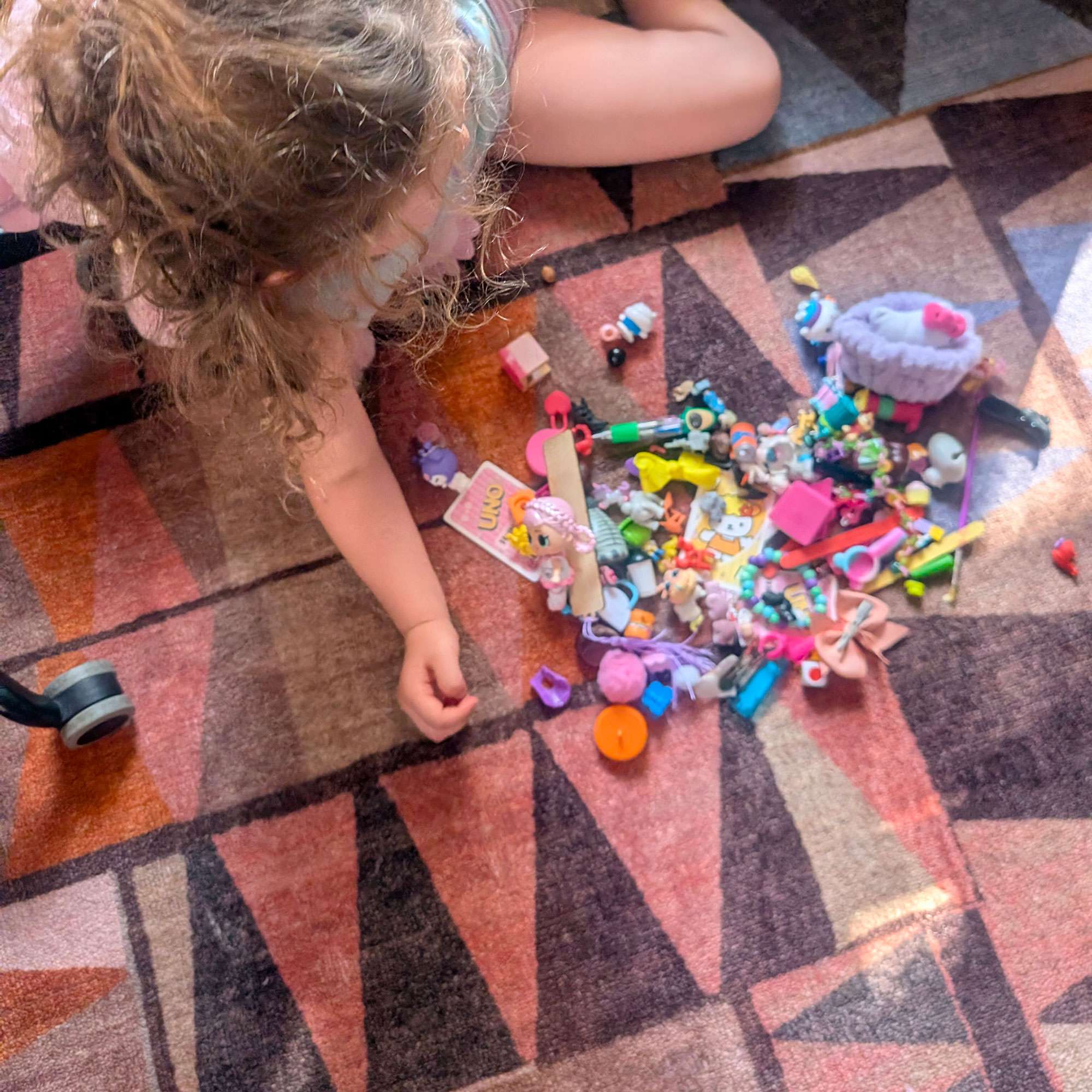 Child playing with small plastic toys on top of abstract patterned rug