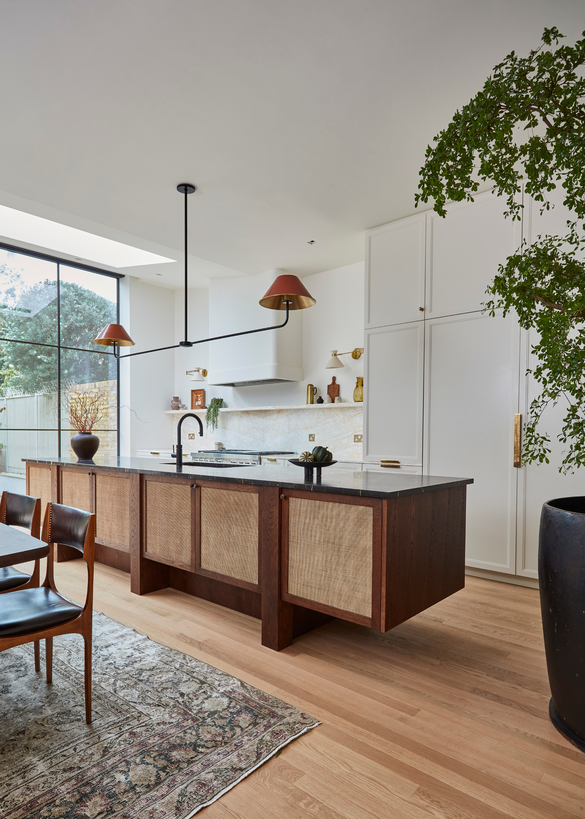 An all wood kitchen showcasing different ones on the island, floor and cabinetry with a long statement centerpiece pendant above.