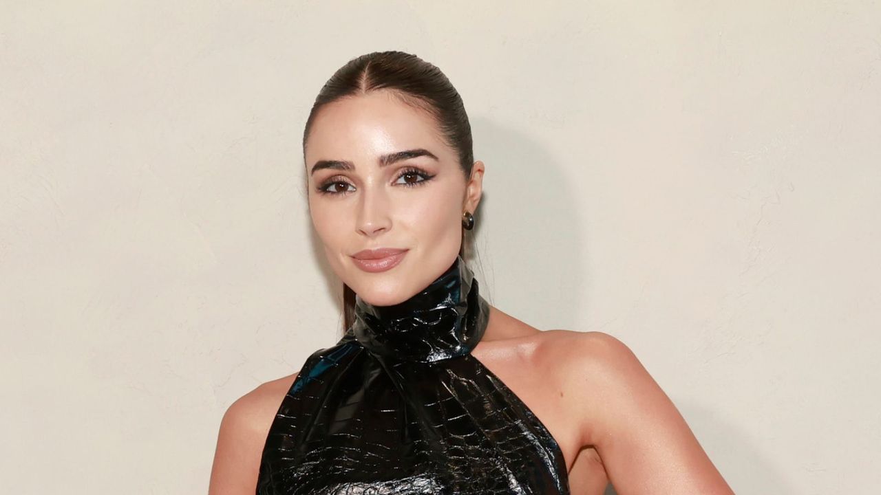 olivia culpo in a black dress on a cream background