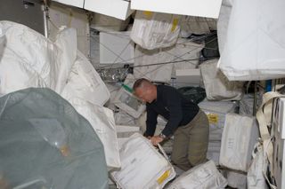 NASA astronaut Doug Hurley, STS-135 pilot, moves around supplies and equipment in the Leonardo Permanent Multipurpose Module (PMM) on July 11, 2011 during the fourth day of flight for Atlantis' four person crew.