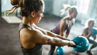 a photo of a woman doing a kettlebell swing in the gym 
