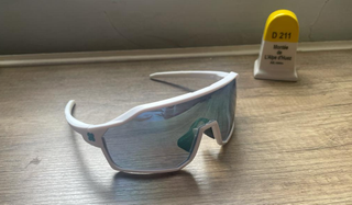 SunGod Velans sunglasses with white frame plus a trinket of Alpe d'Huez road
