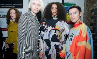 Model wears a black and white check coat, whilst others wear multi-coloured sweatshirts