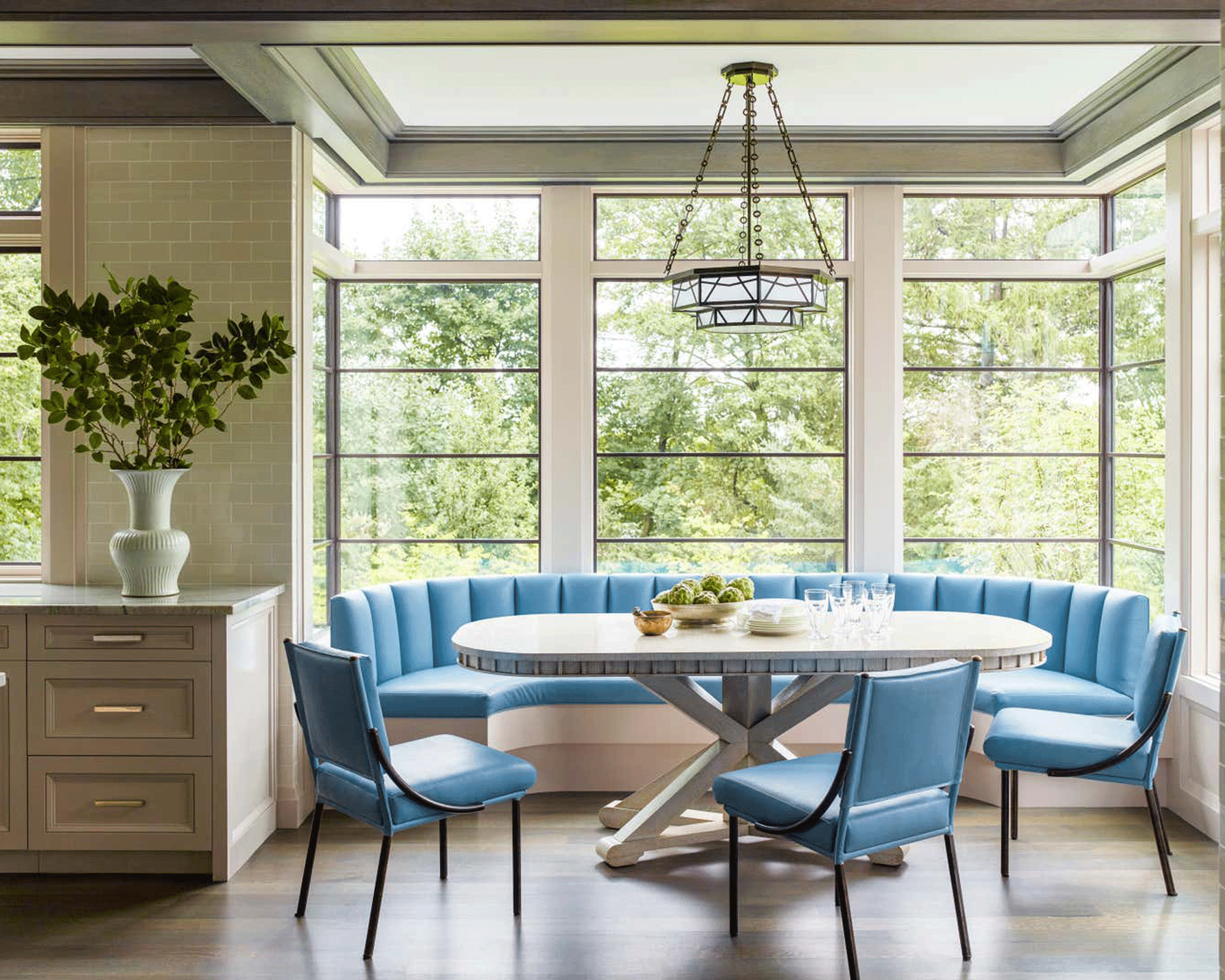 Kitchen with dining nook that has a pale blu. curved banquette and round table