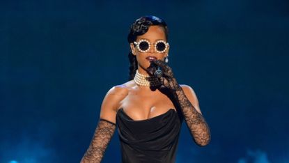 Rihanna performing in a dramatic black dress.