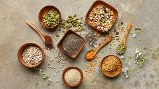 wooden bowls and spoons with different kinds of seed in/on them