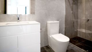 White closed back toilet in contemporary grey bathroom