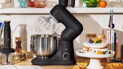 A Beautiful by Drew Barrymore Stand Mixer in a kitchen next to a cake 