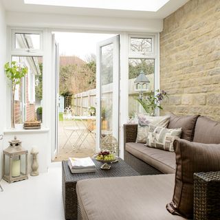 A side extension with a glass roof and double french doors and a brown sofa