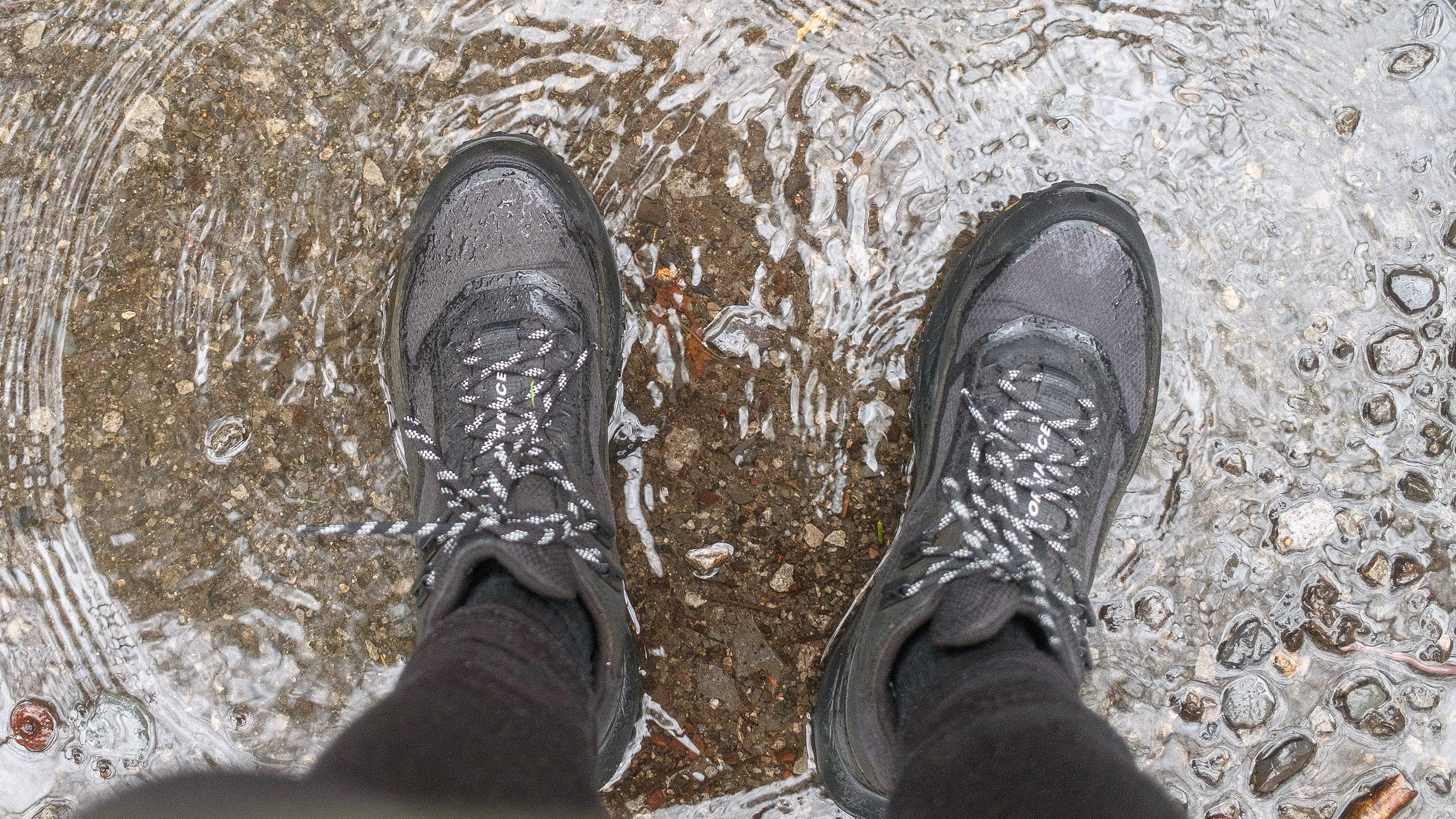 Downward photo of the writer's hiking boots in a puddle