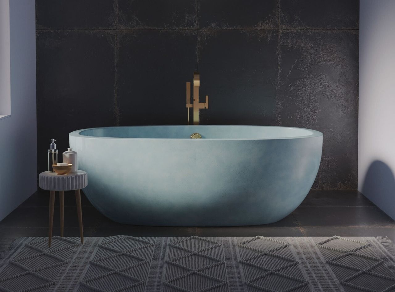 A blue concrete bath tub in a bathroom with a large rug and tiled wall