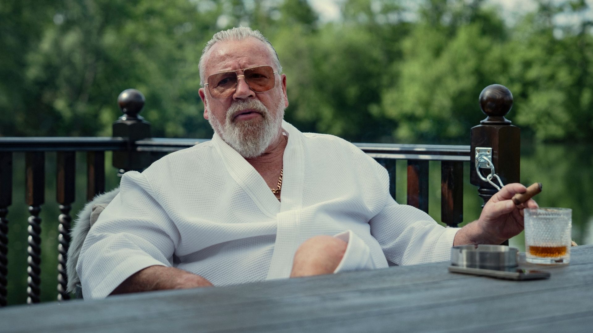 Bobby sits outdoors in a bathrobe holding a cigar