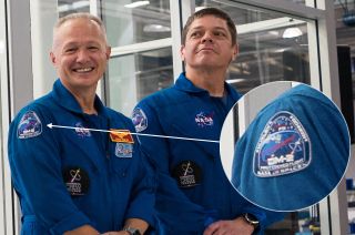 SpaceX Crew Dragon Demo-2 crewmates Doug Hurley (at left) and Bob Behnken debut their mission patch on their NASA flight suits at SpaceX's headquarters in Hawthorne, Calif., Oct. 10, 2019.