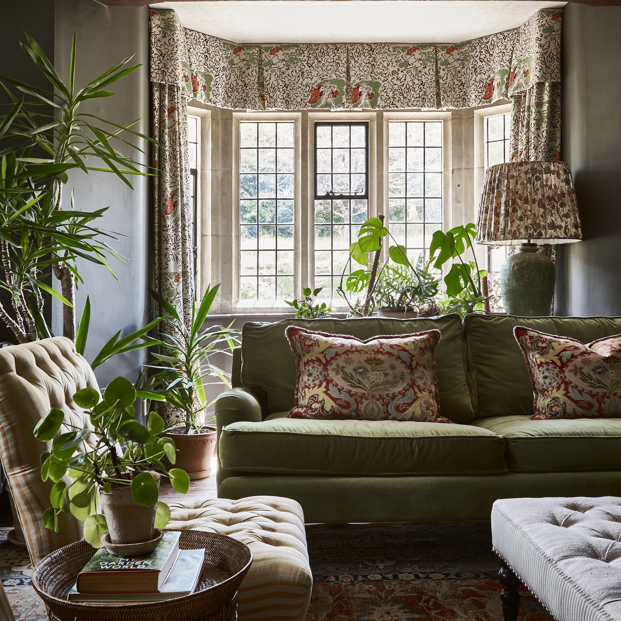 sitting room in country house with square bay window, green sofa, patterned curtains and upholstered seating