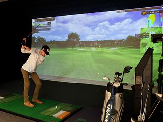 A man swinging a golf club in a golf simulator bay