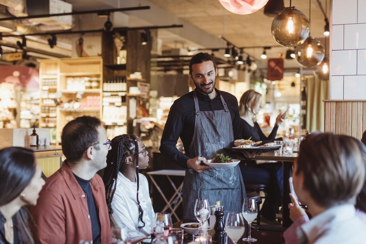 People dining in a restaurant with waiter bringing food