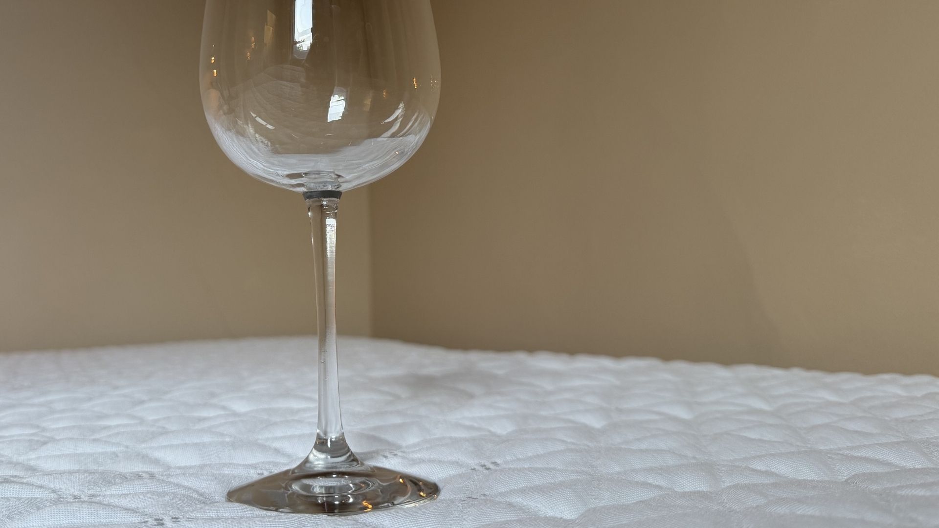 The image shows an empty wine glass placed on the top of a mattress in order to test its motion isolation