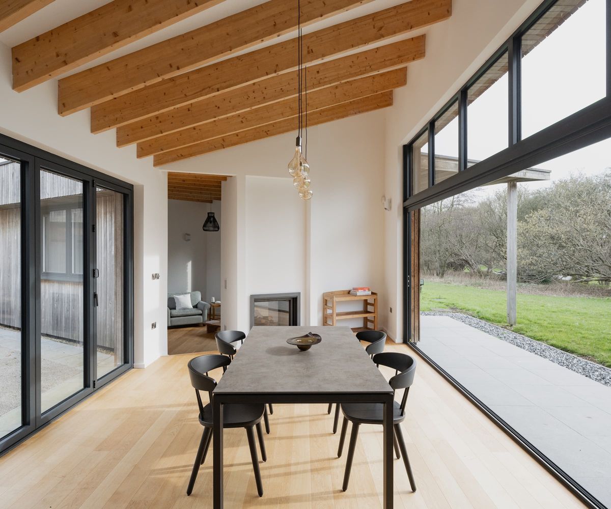 A dining room with timber beams above and large picture windows on either side