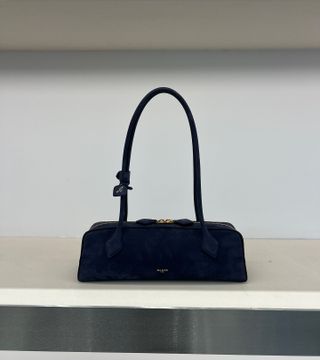 Alaïa's nubuck leather navy blue Le Teckel shoulder bag on a shelf in the brand's Paris flagship store.