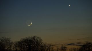 thin crescent moon on the left and a bight venus shining to the upper right.