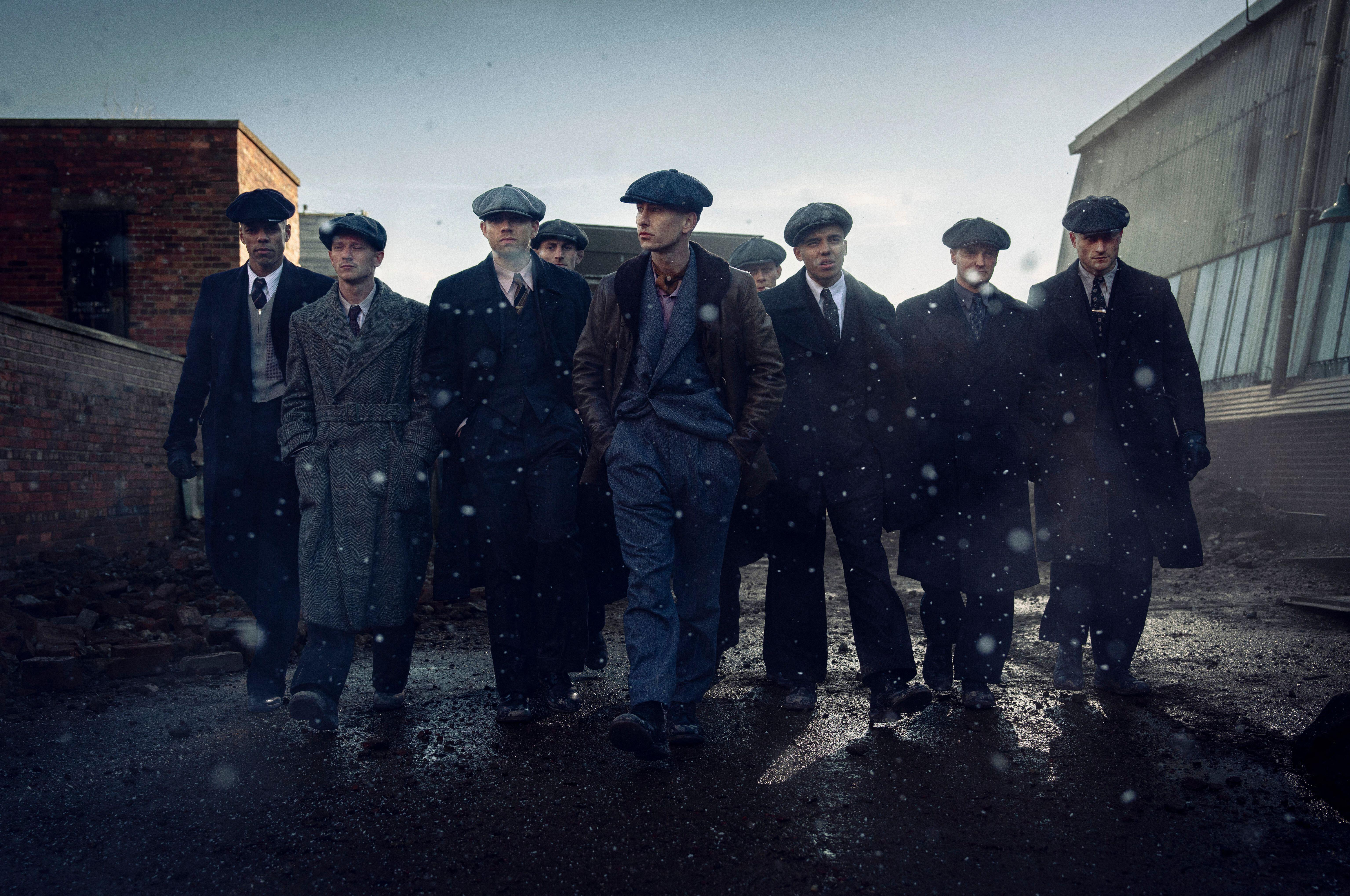 Cast of Peaky Blinders walking in a line down an alley