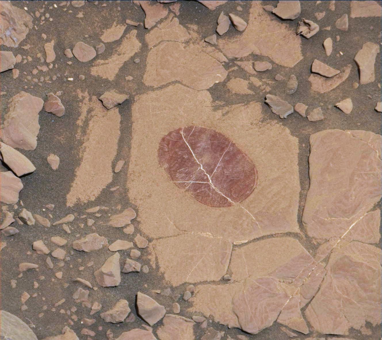 A series of red rocks with a dark circular mark in the middle.