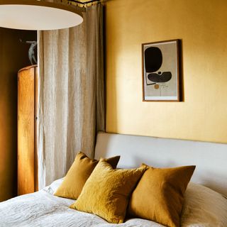 small bedroom colour ideas, gold bedroom with metallic gold bedroom and four poster bed, vintage wardrobe, gold cushions, artwork, oatmeal drapes and bedding, pendant light
