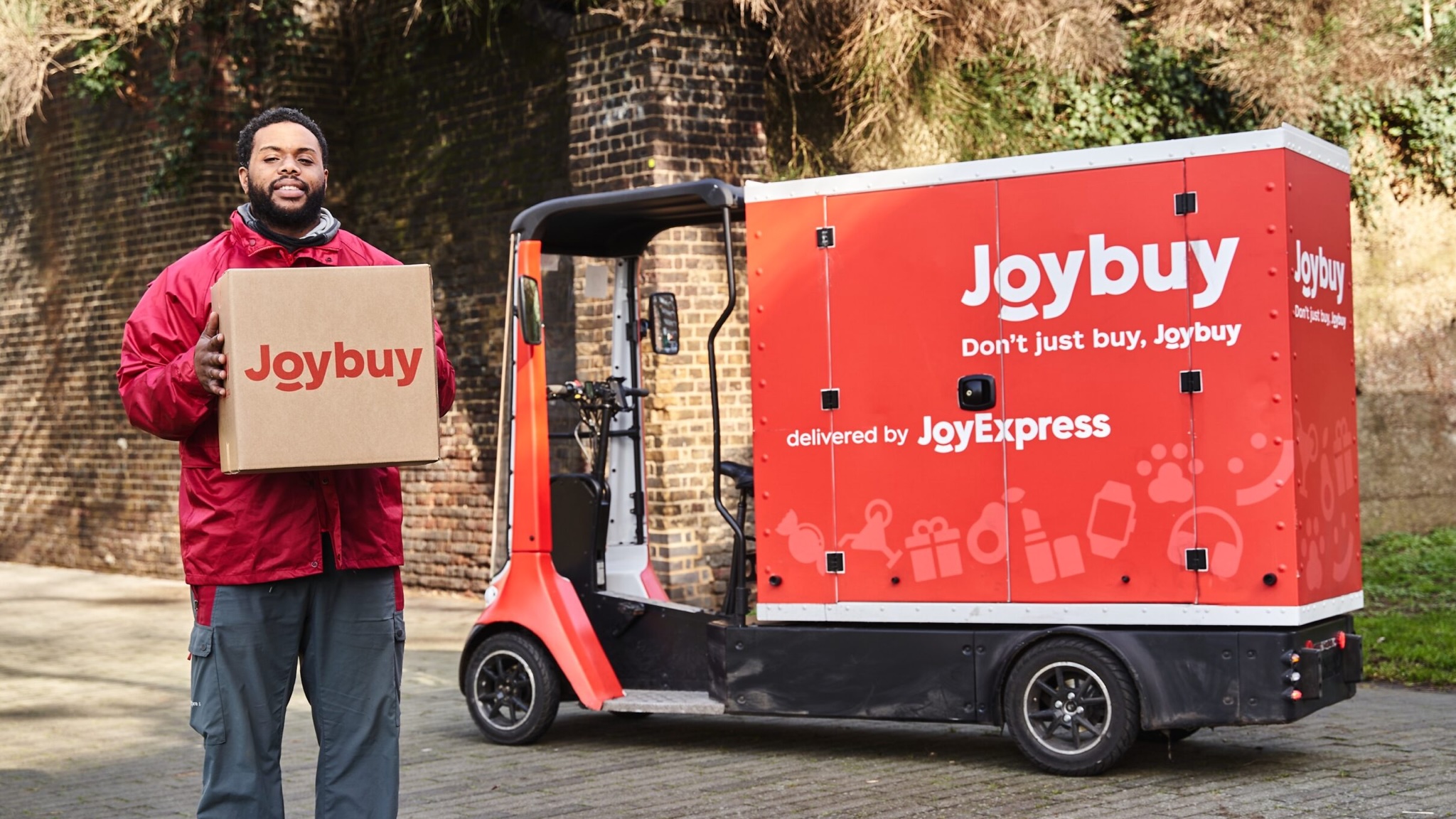 Promotional image for Joybuy showing a smiling man holding a Joybuy parcel in front of a delivery vehicle