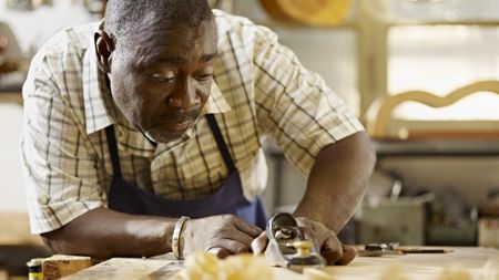 An older man works on a woodworking project.