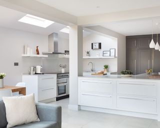 A white kitchen extension with sky lights and a sofa area