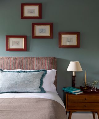 bedroom with blue walls, striped headboard, blue fringed cushion and mid century bedside cabinet