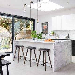 kitchen area with glass door and white wall and marble counter and tables