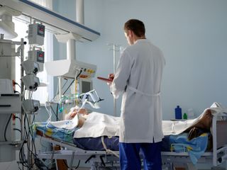 Doctor standing beside ICU patient in bed