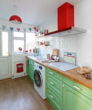kitchen with white wall and wooden floor and green counter with wooden worktop and red chimney