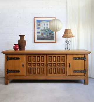 A wood cabinett holds a series of amphoras, a rattan light, in front of a canvas and a paper lantern floating from the ceiling.