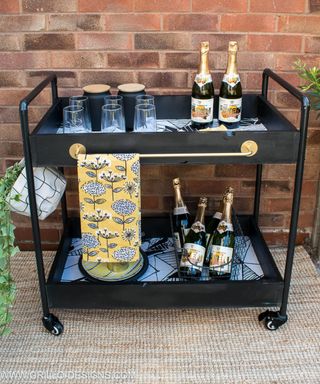 A black diy bar cart with wallpaper inserts in base of drawers