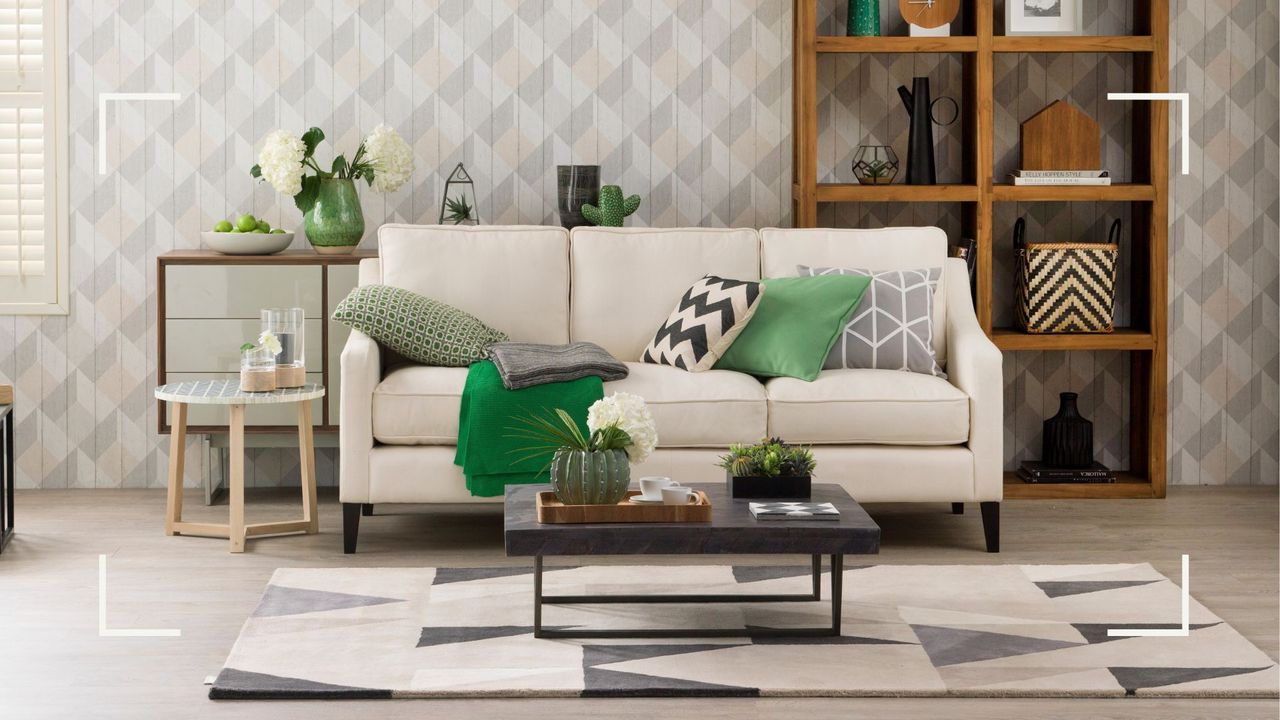 picture of living room with geo patterned wallpaper behind a sofa, bookcase and coffee table to support an article sharing Kelly Hoppen&#039;s tip for creating displays