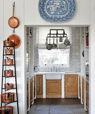 pantry designed in classic style with blue and white tiles and hanging saucepans