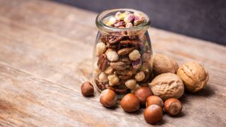 Handful of nuts in a glass jar sitting on wooden counter