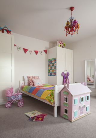 girl bedroom with patchwork bedding, dolls house, bunting and a colourful chandelier