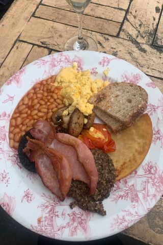 a plate of scottish breakfast haggis, beans, eggs, sausage, toast, mushrooms, tomato