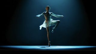 Ana de Armas in wearing white leotard, mid spin, starring in Ballerina. 