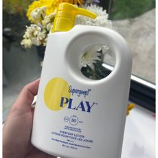 a hand holding a bottle of supergoop play lotion spf