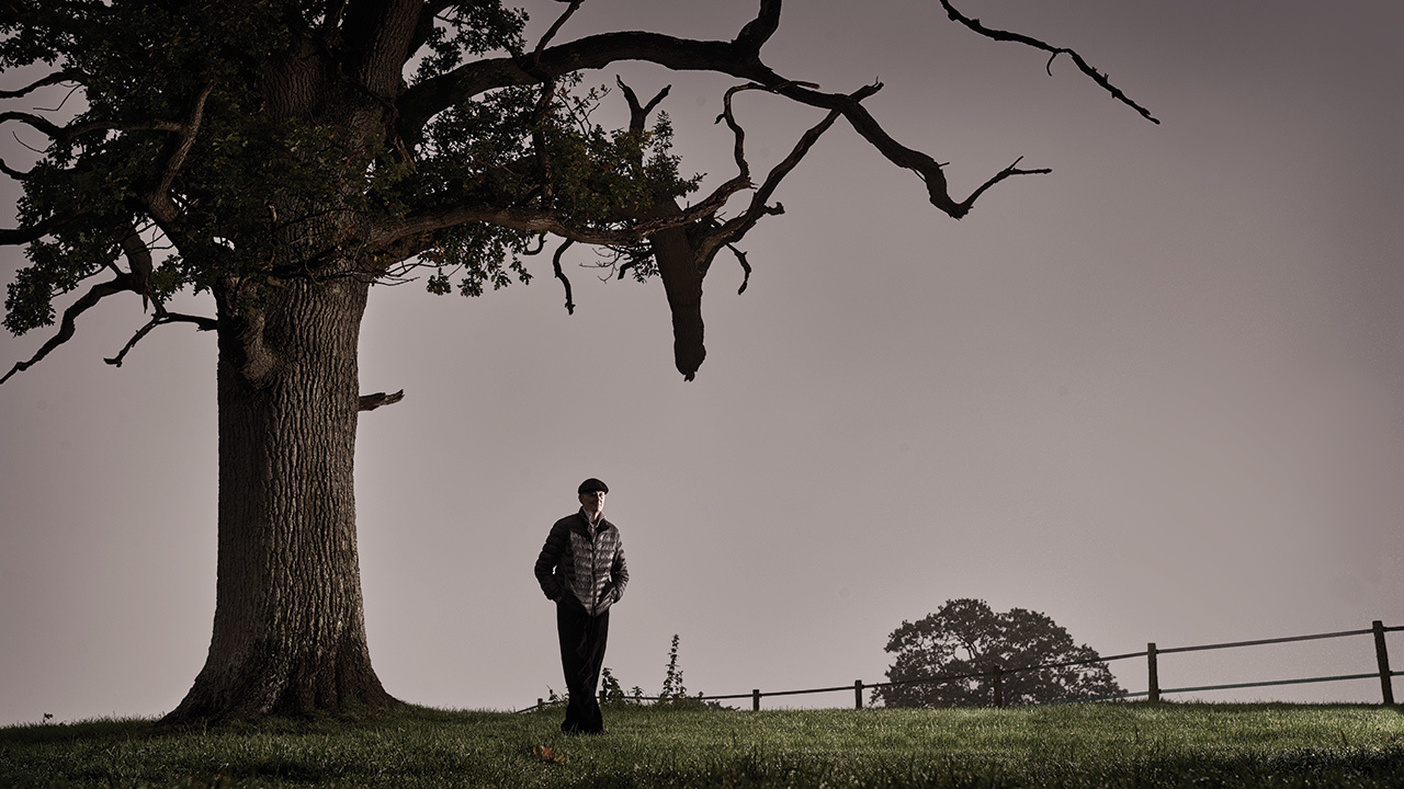 a portrait of peter hammill stood under a tree