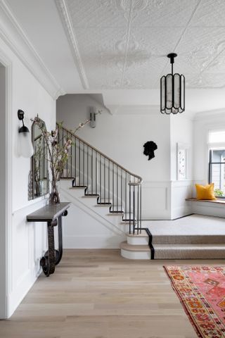 White hallway with neutral stair runner with black edging
