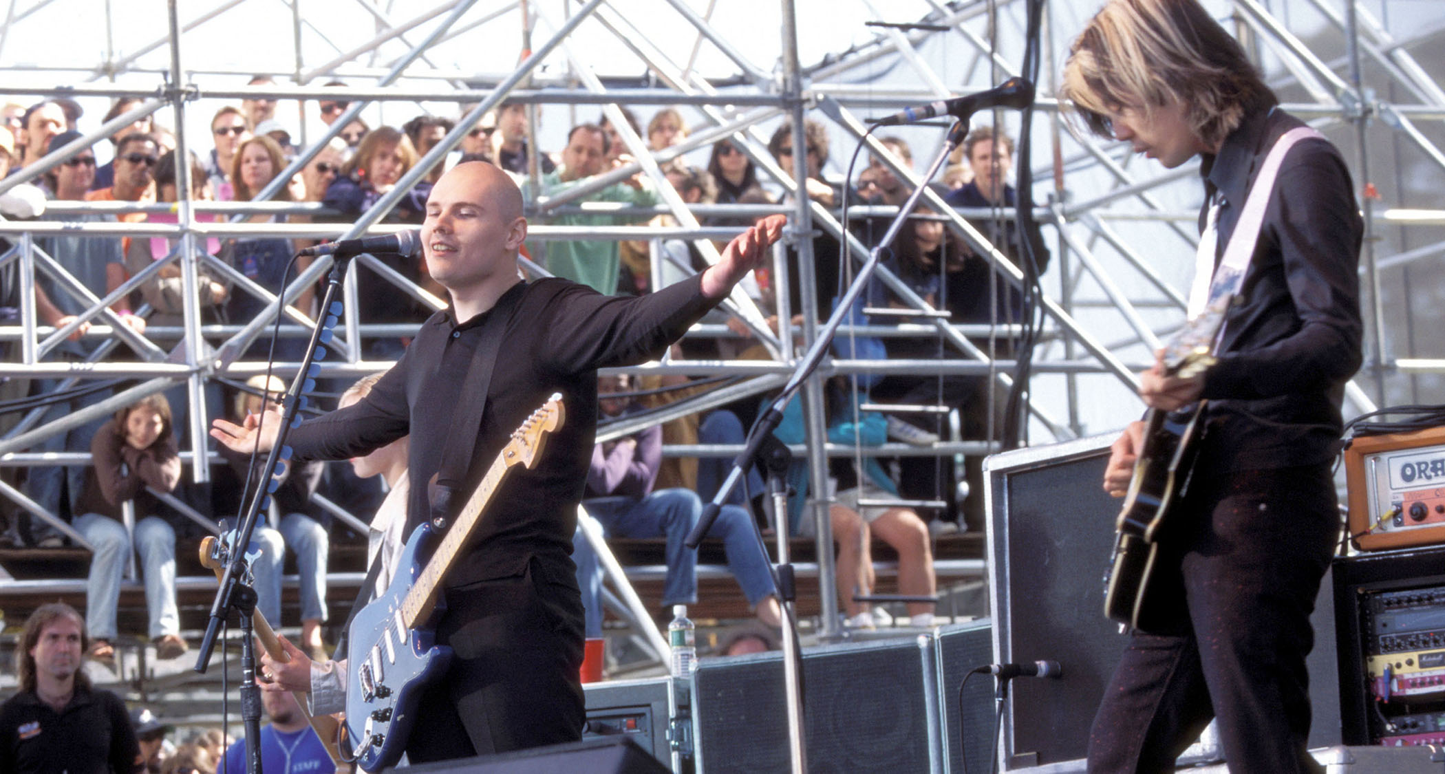 Billy Corgan spreads his arms wide as he performs with Smashing Pumpkins in 1996. He has a Stratocaster. James Iha, viewed in profile, has his Les Paul.