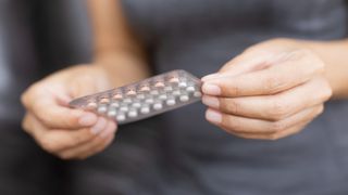 female hormones: a woman holds a blister pack of contraceptive pills